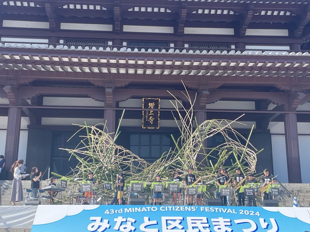 増上寺の大殿と「みなと区民まつり」横断幕を背に演奏する南山ジャズバンド(2024年)